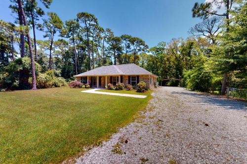 a house with a gravel driveway in front of a yard at Seven Rings in Dauphin Island