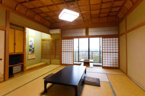 a living room with a table in a room with windows at Wakamiro in Hokuto