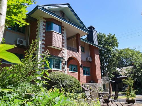 a red brick building with chairs in front of it at Landhaus Dancru Netz in Hakuba