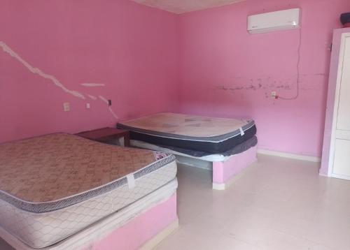 two beds in a room with pink walls at Departamentos el amigo 