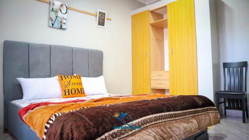 sypialnia z dużym łóżkiem i pomarańczowym kocem w obiekcie Carla's Home w mieście Voi