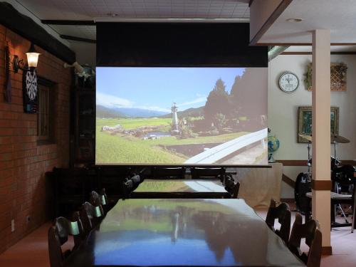 a projection screen in a room with a table and chairs at Landhaus Dancru Netz in Hakuba