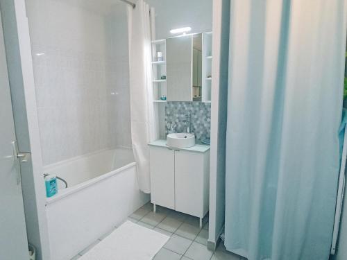 une salle de bain blanche avec une baignoire et un lavabo dans l'établissement Appartement T2 avec garage et piscine à Sète - FR-1-338-484, à Sète