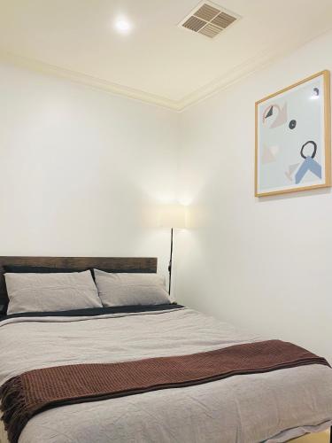 a bed in a white room with a picture on the wall at Bundled Bliss 2 bedroom Condo in Adelaide CBD in Adelaide