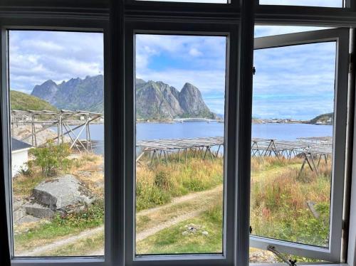 una ventana con vistas al océano y a las montañas en Det Gamle Hotellet Guesthouse en Reine