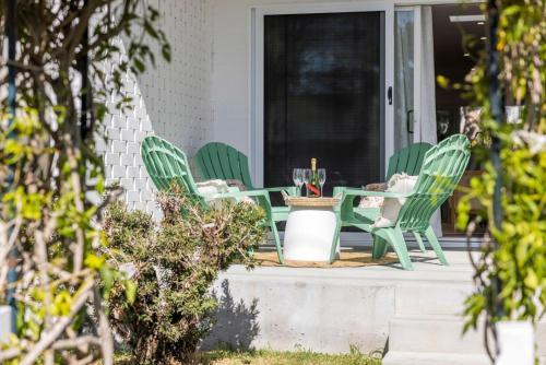 a patio with green chairs and a table on a porch at Nan's Place in Woolgoolga