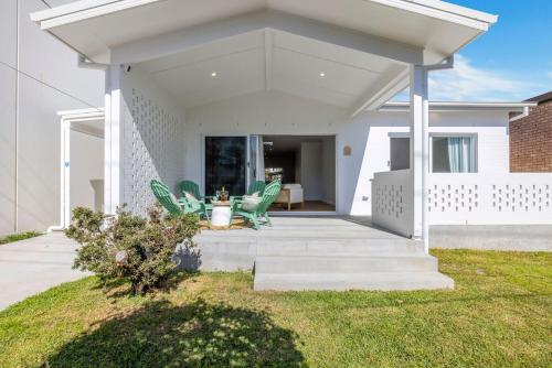 a white house with green chairs on a patio at Nan's Place in Woolgoolga