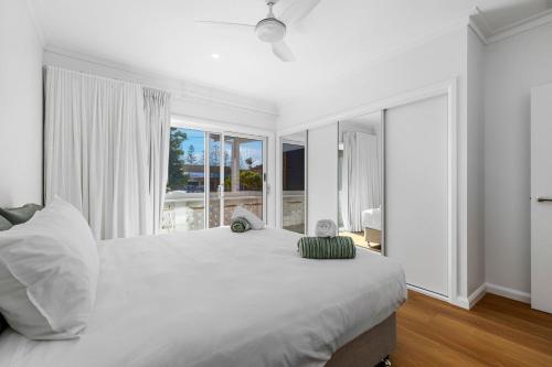 a white bedroom with a large bed and a large window at Nan's Place in Woolgoolga