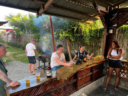 um grupo de pessoas em pé em torno de uma mesa com uma grelha em The Backyard Inn em Moalboal