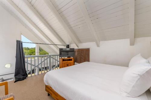 a bedroom with a white bed and a balcony at Tidal House 2 in Ocean Shores
