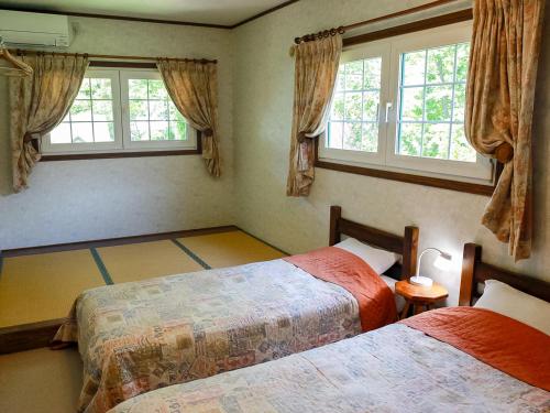 a bedroom with two beds and two windows at Landhaus Dancru Netz in Hakuba