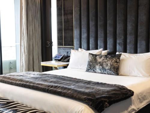 a bedroom with a large bed with a large headboard at Emporium Hotel South Bank in Brisbane