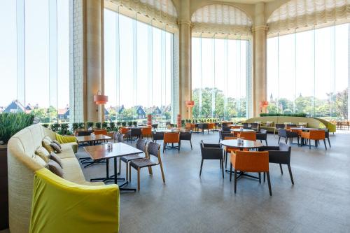 a restaurant with tables and chairs and large windows at Hotel Okura JR Huis Ten Bosch in Sasebo