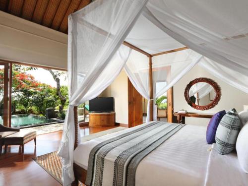 1 dormitorio con cama blanca y espejo en The Shanti Residence by Elite Havens, en Nusa Dua