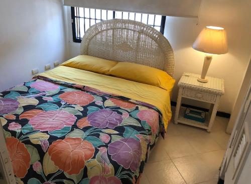a bedroom with a bed with a floral bedspread and a lamp at Casa frente a la playa con wifi in Tucacas