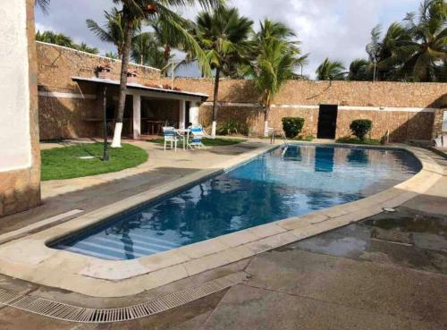 a swimming pool with blue water in front of a house at Casa frente a la playa con wifi in Tucacas