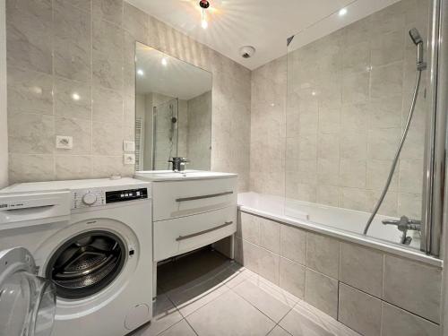 une salle de bain avec un lave-linge et une baignoire dans l'établissement Charmant 3 pièces rénové avec balcon, ascenseur et garage en plein centre d'Annecy - FR-1-432-85, à Annecy