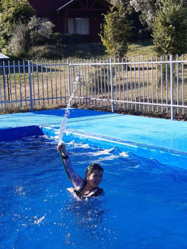 Un niño está en una piscina con una manguera de agua en Cabañas Alto Caburgua 2 dorm, en Caburgua