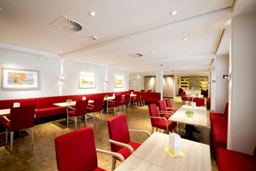 a restaurant with red chairs and tables at Heinrich Pesch Hotel in Ludwigshafen am Rhein