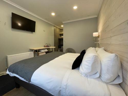 a bedroom with a large bed with white pillows at Hostal Boutique Puerta Roja in Punta Arenas