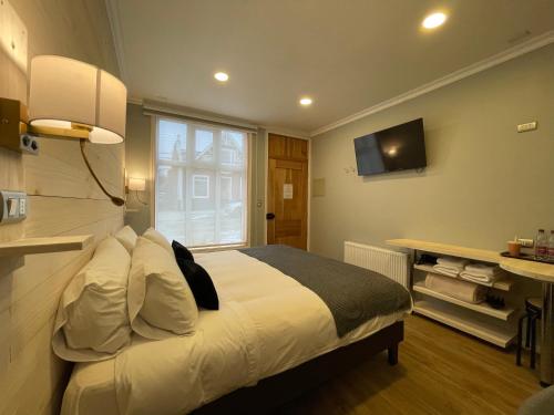 a bedroom with a large bed and a television at Hostal Boutique Puerta Roja in Punta Arenas