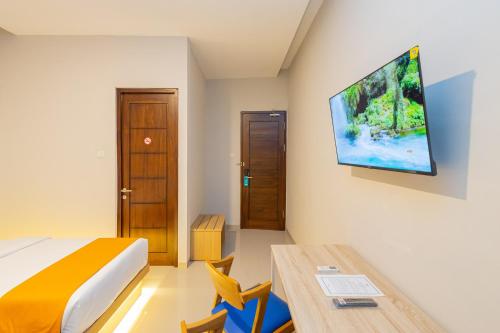 a bedroom with a bed and a tv on the wall at Sans Hotel Bobosini Malang by RedDoorz in Malang