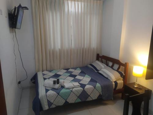 a small bedroom with a bed and a window at Ambigua Hospedaje in Trujillo