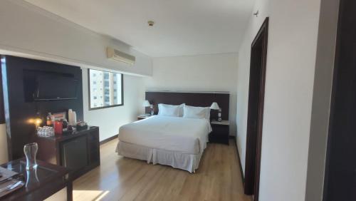 um quarto com uma grande cama branca e pisos em madeira em Quarto privativo em hotel 4 estrelas no Itaim em São Paulo