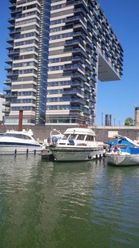 two boats docked in the water in front of a tall building at Fantasie Boot EINHORN in Cologne