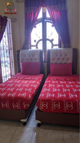 2 camas en una habitación con ventana en Hotel Garuda en Rambah