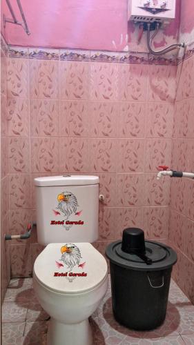 Baño rosa con aseo y cubo de basura en Hotel Garuda en Rambah