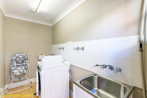 una cucina con lavandino e frigorifero bianco di Martys 7 2 Intrepid Cl - pool , air con , Wi-Fi and linen a Nelson Bay