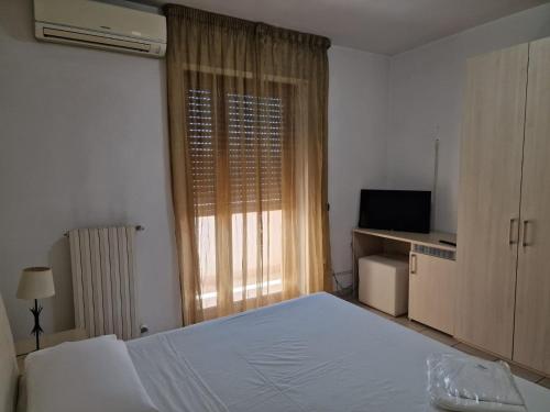 1 dormitorio con 1 cama blanca y TV en JAPIGIA ROOMS, en Lecce