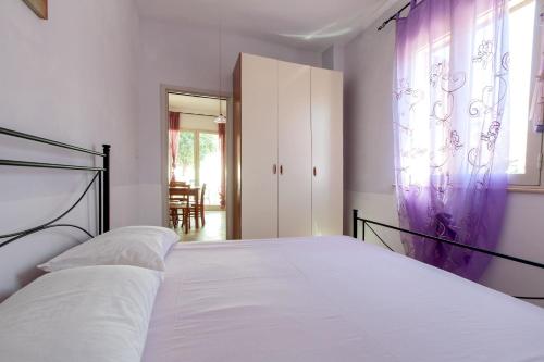 トッレ・パリにあるCasa Dalilaのベッドルーム1室(白いシーツと紫色のカーテンが備わるベッド1台付)