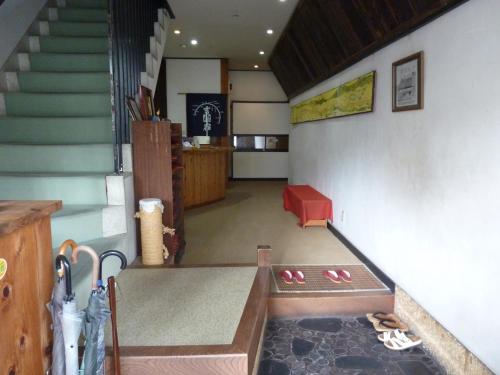 um corredor com escadas e um quarto com sapatos no chão em Taiya Ryokan em Fuji