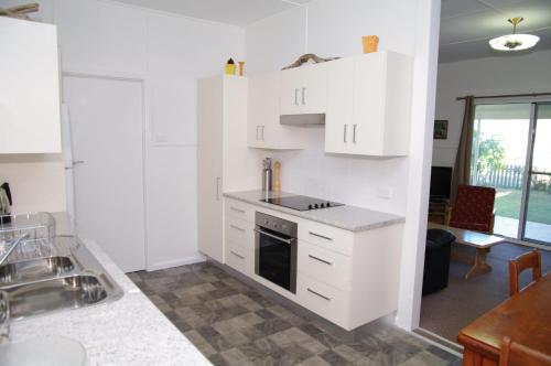 eine Küche mit weißen Schränken und einem Herd in der Unterkunft Fleur Cottage, 7 Willow Street in Crescent Head