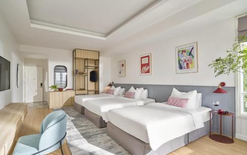 ein Hotelzimmer mit 2 Betten und einem Sofa in der Unterkunft The Postcard Hotel in Hạ Long