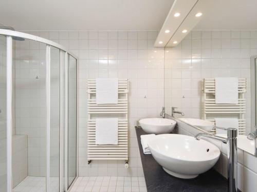 a white bathroom with two sinks and a shower at Frederikenhof in Kampen