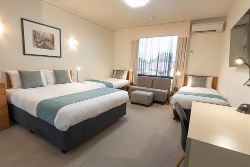 a hotel room with two beds and a chair at Sovereign Park Motor Inn in Ballarat