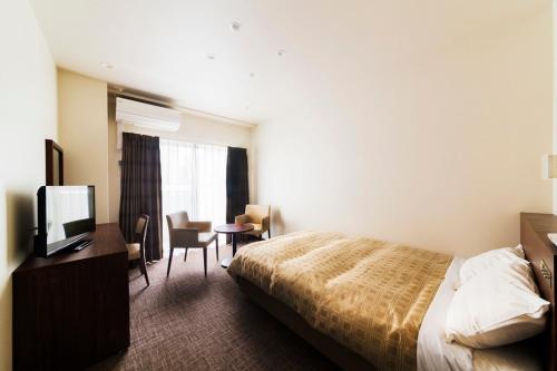 a hotel room with a bed and a desk and a television at Kansai Airport First Hotel in Izumi-Sano