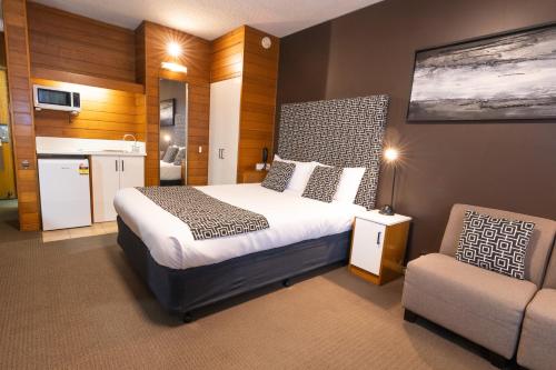 a bedroom with a bed and a chair in it at Sovereign Park Motor Inn in Ballarat