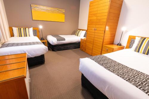 a hotel room with two beds and a dresser at Sovereign Park Motor Inn in Ballarat