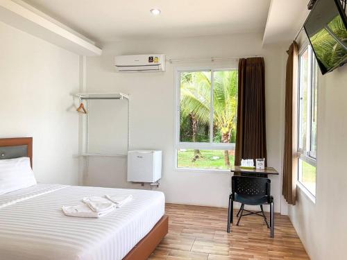 een slaapkamer met een bed, een bureau en een raam bij My Heaven Resort in Trang