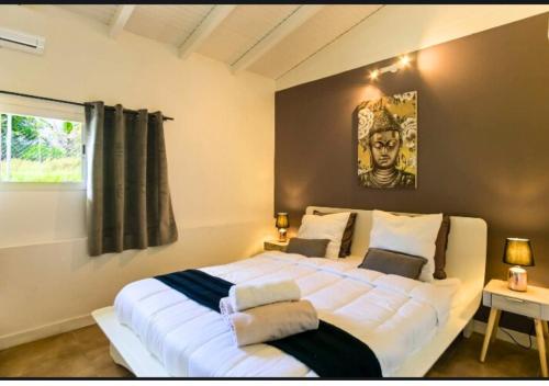 uma grande cama branca num quarto com uma janela em Kajoane's villa em Sainte-Anne