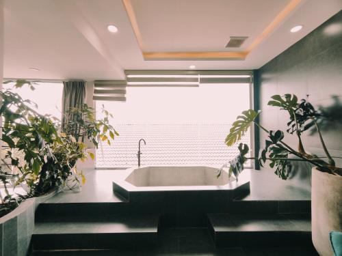 Khách Sạn Greenhills في Xuan An: حمام مع حوض ونباتات خزفية