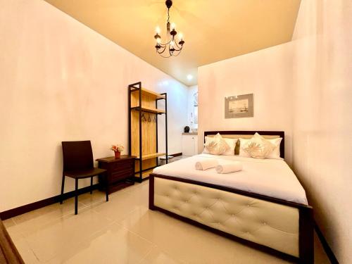 a bedroom with a bed with a chair and a chandelier at E&R Airport Hotel in Dumaguete