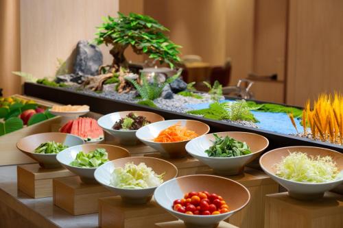 a buffet with bowls of vegetables and a fish tank at Guangzhou Wogo Yuanbao Hotel-Zhujiang New Town-Free Canton Fair Shuttle Bus & Overseas Buyer Registration Services in Guangzhou