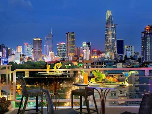 a balcony with two tables and chairs and a city skyline at Elios Hotel in Ho Chi Minh City