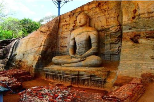 a large statue on the side of a stone wall at ARANI HOMESTAY in Polonnaruwa
