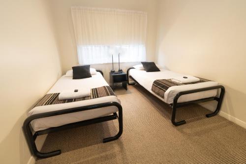 two twin beds in a room with a window at Sovereign Park Motor Inn in Ballarat